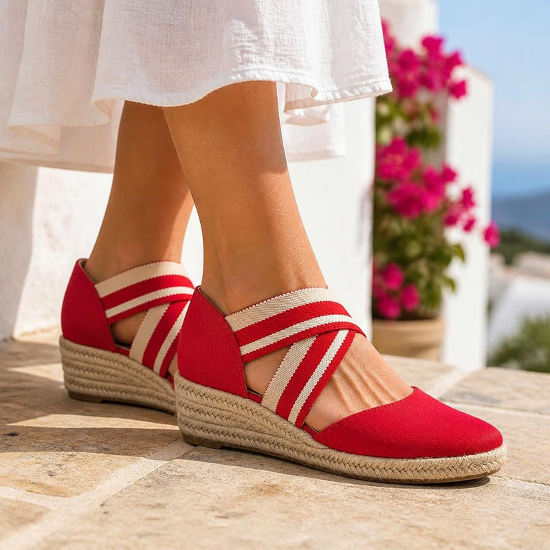 The Capri Espadrille Wedge in Red, worn on a terrace